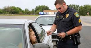 A police officer stood outside a car window, meticulously checking the driver’s documents for any discrepancies that could result in a traffic ticket.